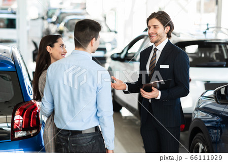 Salesman Offering Couple Car Standing In Office 66111929