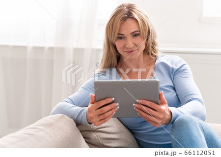 Online chat and dating. Mature woman watching digital tablet with smile Online chat and dating. Mature woman watching digital tablet with smile 66112051