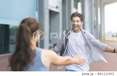 Man greeting girlfriend after arriving to airport, spreading hands for embrace 66112403