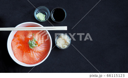Top view and focus to Salmon with Japanese rice or Salmon Ikura Don in paper dish from delivery restaurant on black Table cloths Top view and focus to Salmon with Japanese rice or Salmon Ikura Don in paper dish from delivery restaurant on black Table cloths 66115123