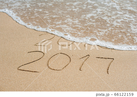 New Year 2017 is coming concept - inscription 2016 and 2017 on a beach sand, the wave is almost covering the digits 2016 New Year 2017 is coming concept - inscription 2016 and 2017 on a beach sand, the wave is almost covering the digits 2016 66122159