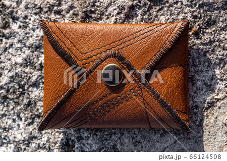 Close-up of handmade brown leather card wallet on stone background. Unisex accessory. Close-up of handmade brown leather card wallet on stone background. Unisex accessory. 66124508