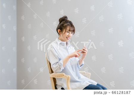 クラシックチェアに座りスマホを眺める女性（笑顔） 66128187