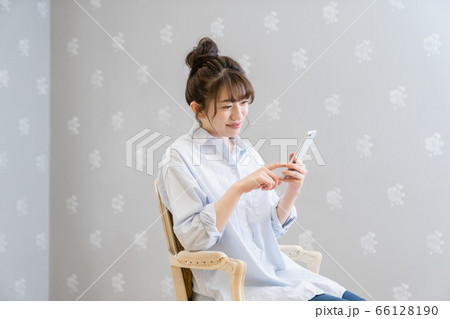 クラシックチェアに座りスマホを眺める女性（笑顔） 66128190