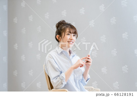 クラシックチェアに座りスマホを眺める女性（笑顔） 66128191