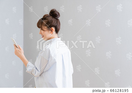 こちらに背中を向けてスマホを眺める女性（横顔） 66128195