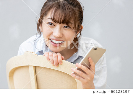 クラシックチェアに座りスマホを眺める女性（笑顔） 66128197