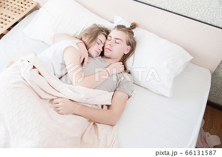 Portrait of a sleeping young couple on a bed with white bedding. Pandemic and Isolation and Quarantine Concept. Sleep as a quarantine pastime 66131587
