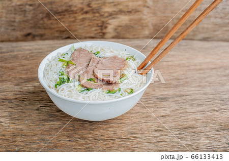 A bowl of Traditional Vietnamese beef soup Pho Bo at the dark old wooden background A bowl of Traditional Vietnamese beef soup Pho Bo at the dark old wooden background 66133413