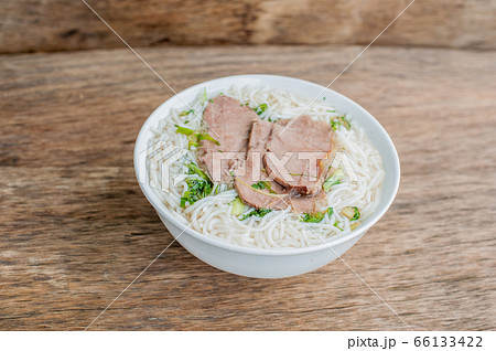 A bowl of Traditional Vietnamese beef soup Pho Bo at the dark old wooden background 66133422