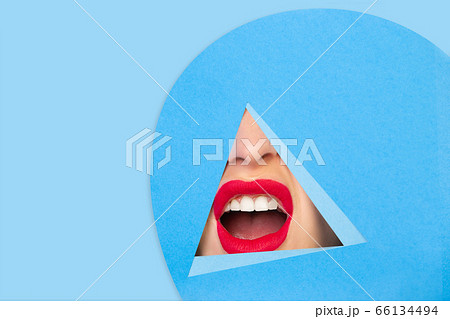 Female red lips peeking throught triangle in blue background 66134494