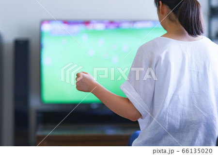 家でスポーツをテレビ観戦する若い女性のイメージ【プロサッカーの動画配信サービス】 66135020