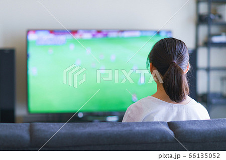 家でスポーツをテレビ観戦する若い女性のイメージ プロサッカーの動画配信サービス の写真素材