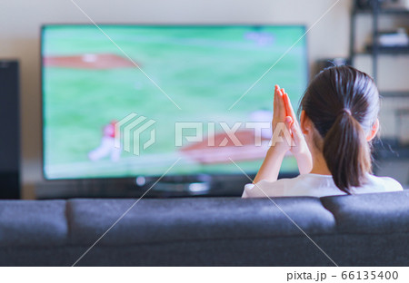 家でスポーツをテレビ観戦する若い女性のイメージ【プロ野球の動画配信サービス】 66135400