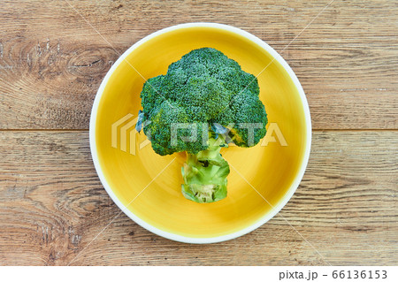 green broccoli inflorescence on a yellow plate on green broccoli inflorescence on a yellow plate on 66136153