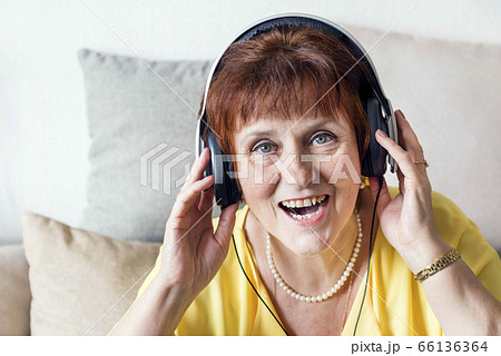 white adult woman in headphones listening to music and singing, portrait of a woman close up 66136364