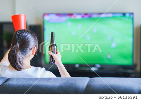 家でスポーツをテレビ観戦する若い女性のイメージ【プロサッカーの動画配信サービス】 66136591