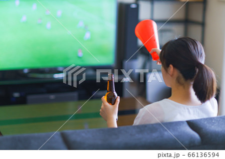 家でスポーツをテレビ観戦する若い女性のイメージ【プロサッカーの動画配信サービス】 66136594