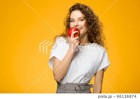 Pretty curly girl with red apple in studio Pretty curly girl with red apple in studio 66136874