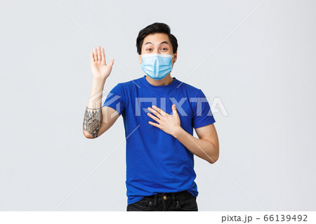 Different emotions, social distancing, self-quarantine on covid-19 and lifestyle concept. Sincere and honest asian guy in medical mask telling truth, making promise with hand raised and one on heart 66139492