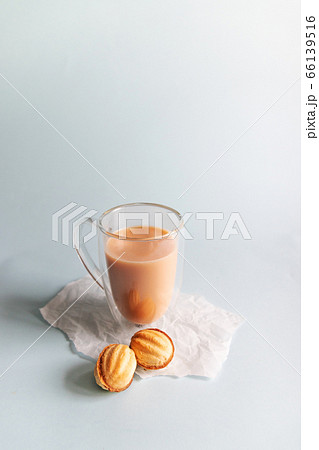 Hot coffee with milk in a glass cup and cookies on a blue background. Vertical photo 66139516
