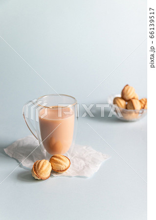 Hot coffee with milk in a glass cup and cookies on a blue background with copy space. Vertical photo 66139517