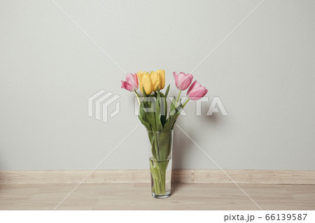 Beautiful yellow and pink tulips in glass vase on the floor in the room 66139587