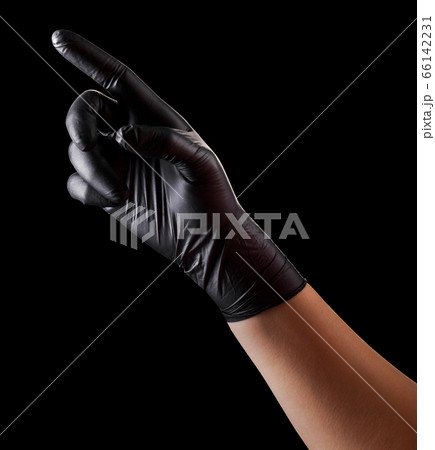 Hand in black gloves with index finger pointing or touching something on black 66142231