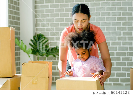 Mother and American African girl help together to set or pack paper box or carton move new house 66143128
