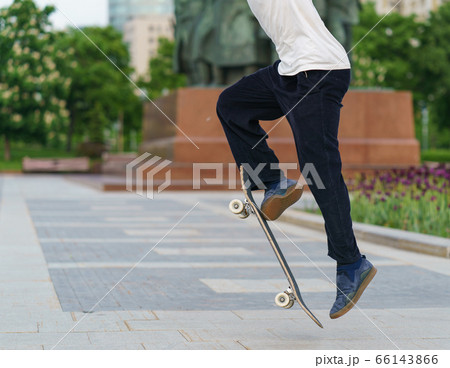 Young skateboarder performs a trick on a city street in sunny spring day. Extreme sports is very popular among youth. Healthy ifestyle during coronavirus pandemic time. 66143866