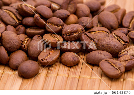 Scattering of roasted coffee beans on top of a wooden cutting board Scattering of roasted coffee beans on top of a wooden cutting board 66143876