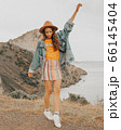 Beautiful girl in a hat on a summer vacation in the mountains on nature. Blue sky and sea. 66145404