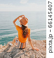 Beautiful girl in a hat on a summer vacation in the mountains on nature. Blue sky and sea. 66145407