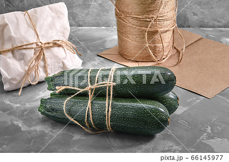 A bunch of zucchini on a gray background with a paper bag for delivery, food delivery, environmental packaging. Copy space, fresh vegetables. 66145977