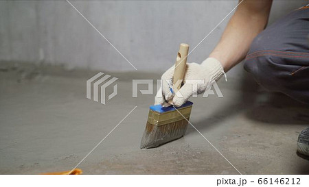 Waterproofing concrete mortar. The master puts waterproofing on a concrete floor with a brush. 66146212