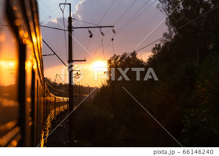 An electric locomotive. The train takes me into the sunset. Railway tracks curve. 66146240
