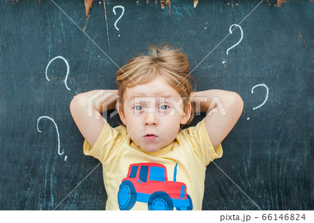Top view of a little blond kid boy with question mark on blackboard. Concept for confusion, brainstorming and choice 66146824