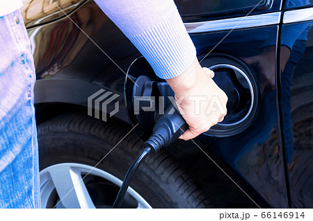 Woman charging modern electric car battery 66146914