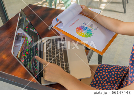 Woman pointing at financial candlestick graph on laptop at cafeteria 66147448