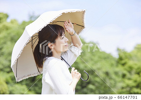 青空の下で日傘をさす女性 66147701