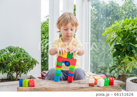 Cute little kid boy with playing with lots of colorful plastic blocks indoor. Active child having fun with building and creating of tower. Promotion of skills and creativity 66151626