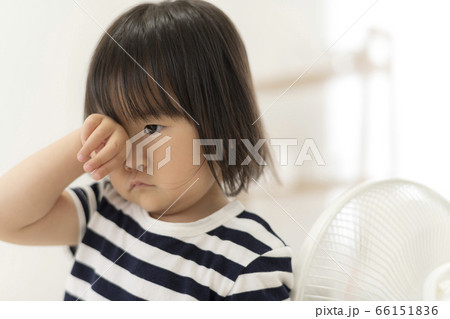 遊び疲れて眠たくなって目を擦る女の子の写真素材