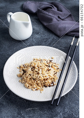 Brown and unpeeled rice on a plate with chopsticks. Dark concrete background. Copy space. 66154702