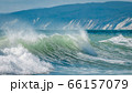 Sea swell wave with spray on top coming to beach 66157079