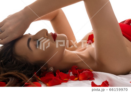 Sexy Brunette lying in bed with rose petals 66159970