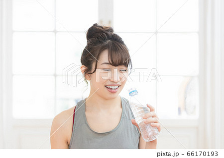 トレーニングウェアを着てミネラルウォーターを持つ女性 66170193