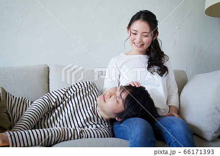 女性の膝枕で寝る若い男性の写真素材