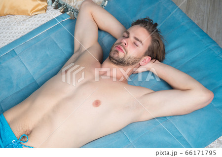 Macho with bare torso, chest lie on blue bed cover Macho with bare torso, chest lie on blue bed cover 66171795