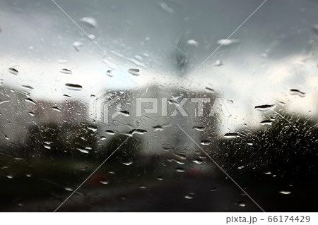 Raindrops on the glass. Blurry rainy gray background and city view. 66174429