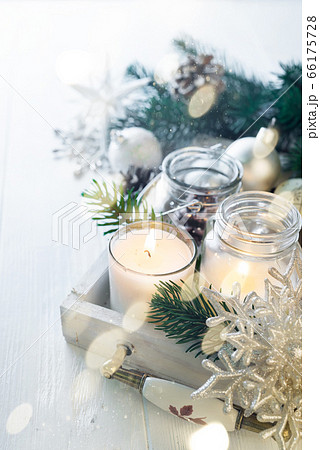 Burning candle and Christmas decoration over snow and wooden background, elegant low-key shot with festive mood Burning candle and Christmas decoration over snow and wooden background, elegant low-key shot with festive mood 66175728